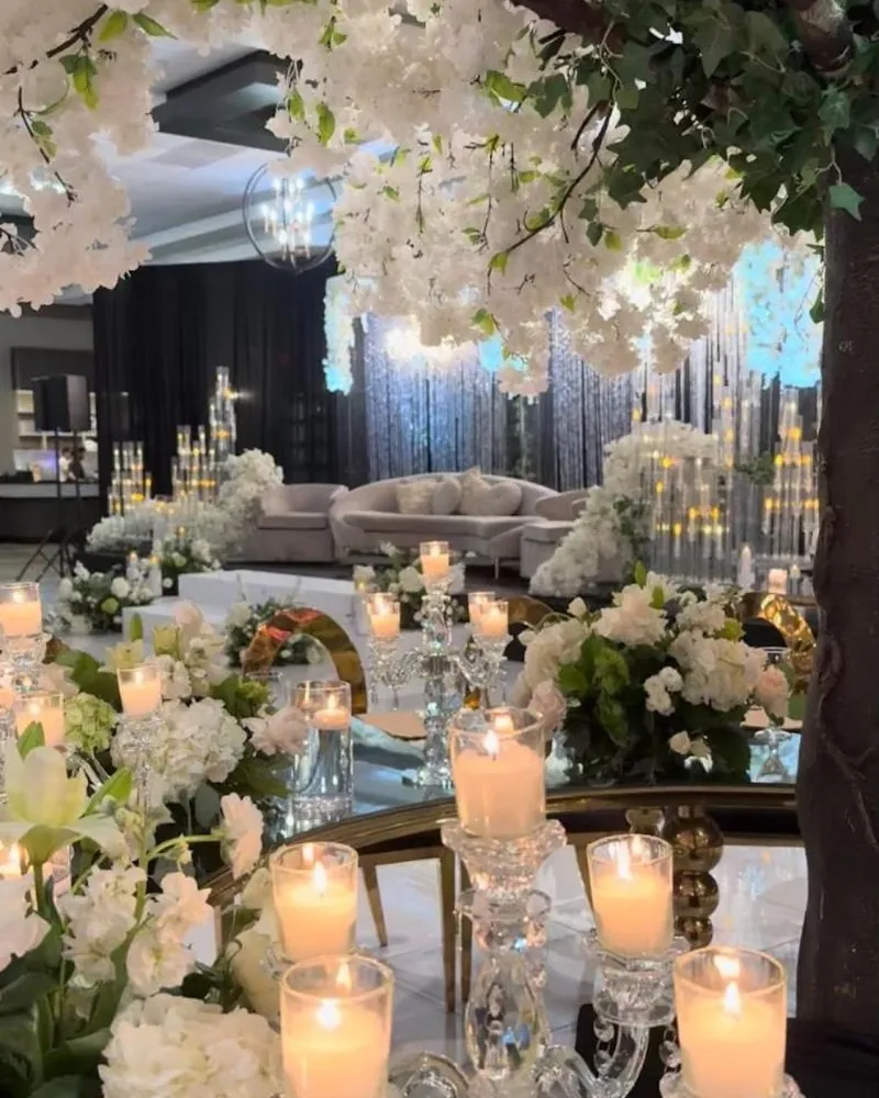 Table under a canopy of white blossom branches with a lit crystal candelabra and white flowers