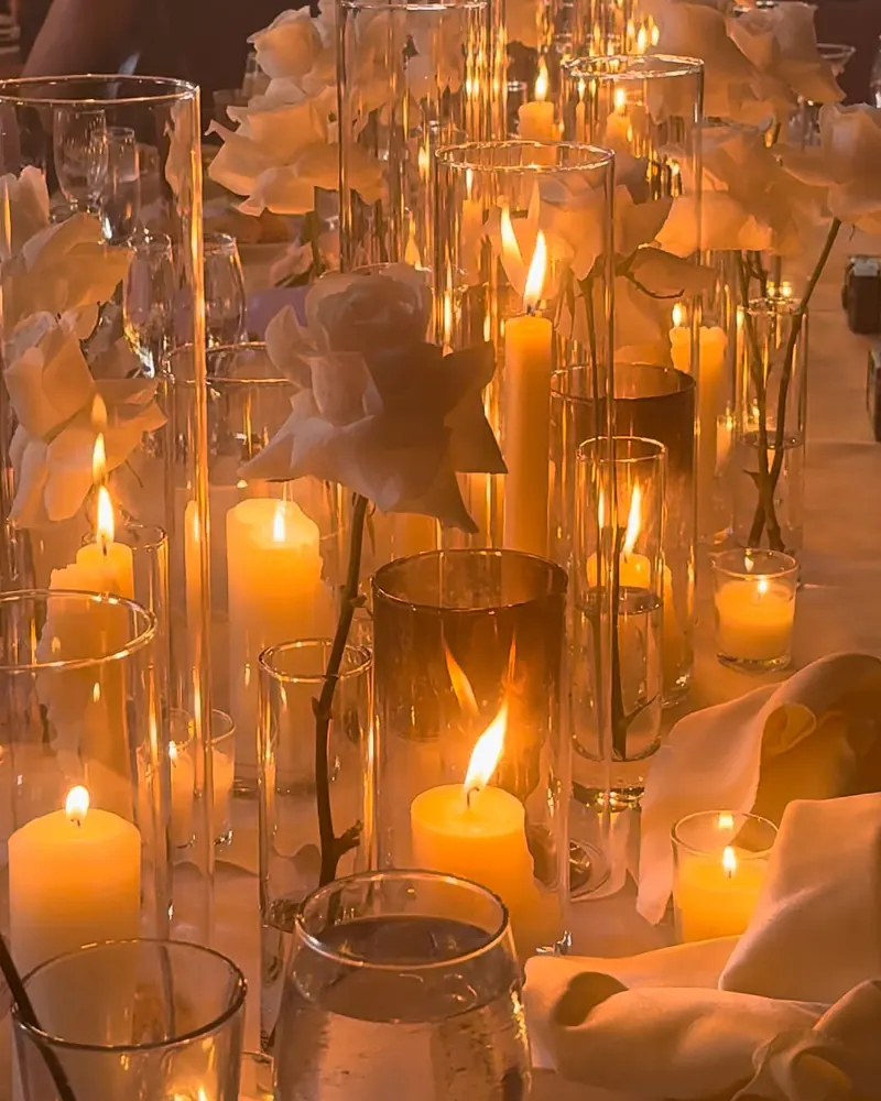 Clusters of pillar candles in tall glass among white flowers