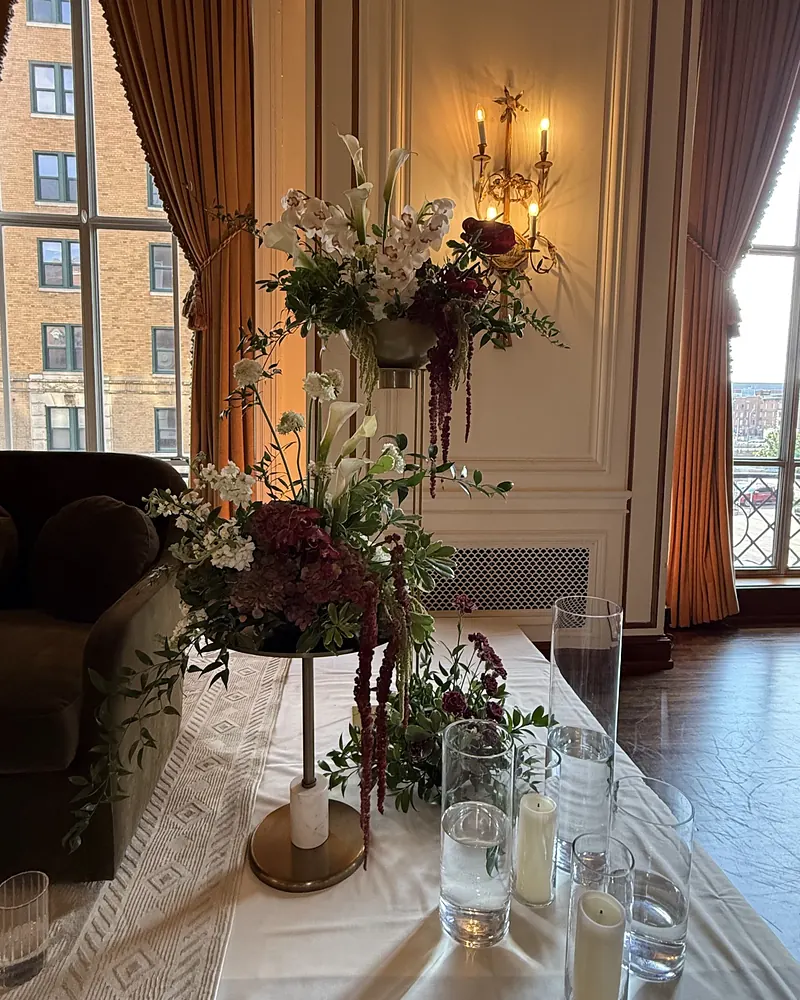 Tall garden-style centerpiece with lilies and trailing amaranthus on a long table