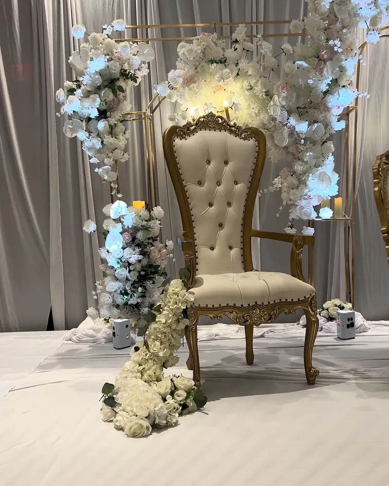 Gold and ivory chair framed by white florals against soft gray drape