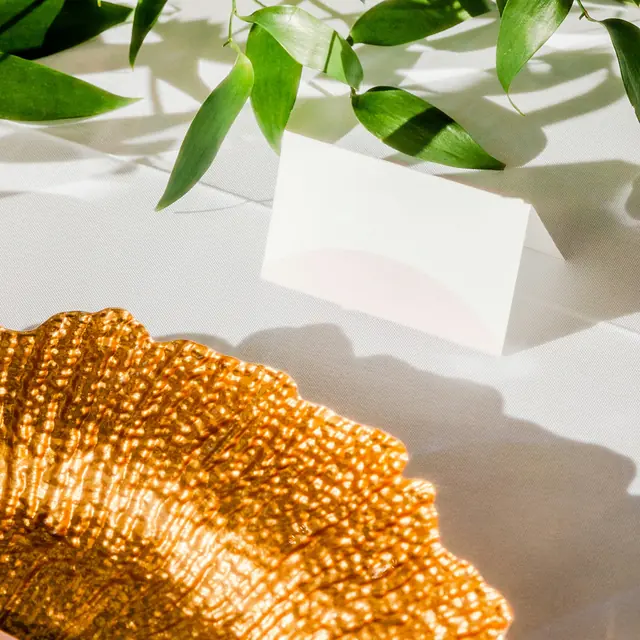 Gold beaded charger with a blank place card and greenery